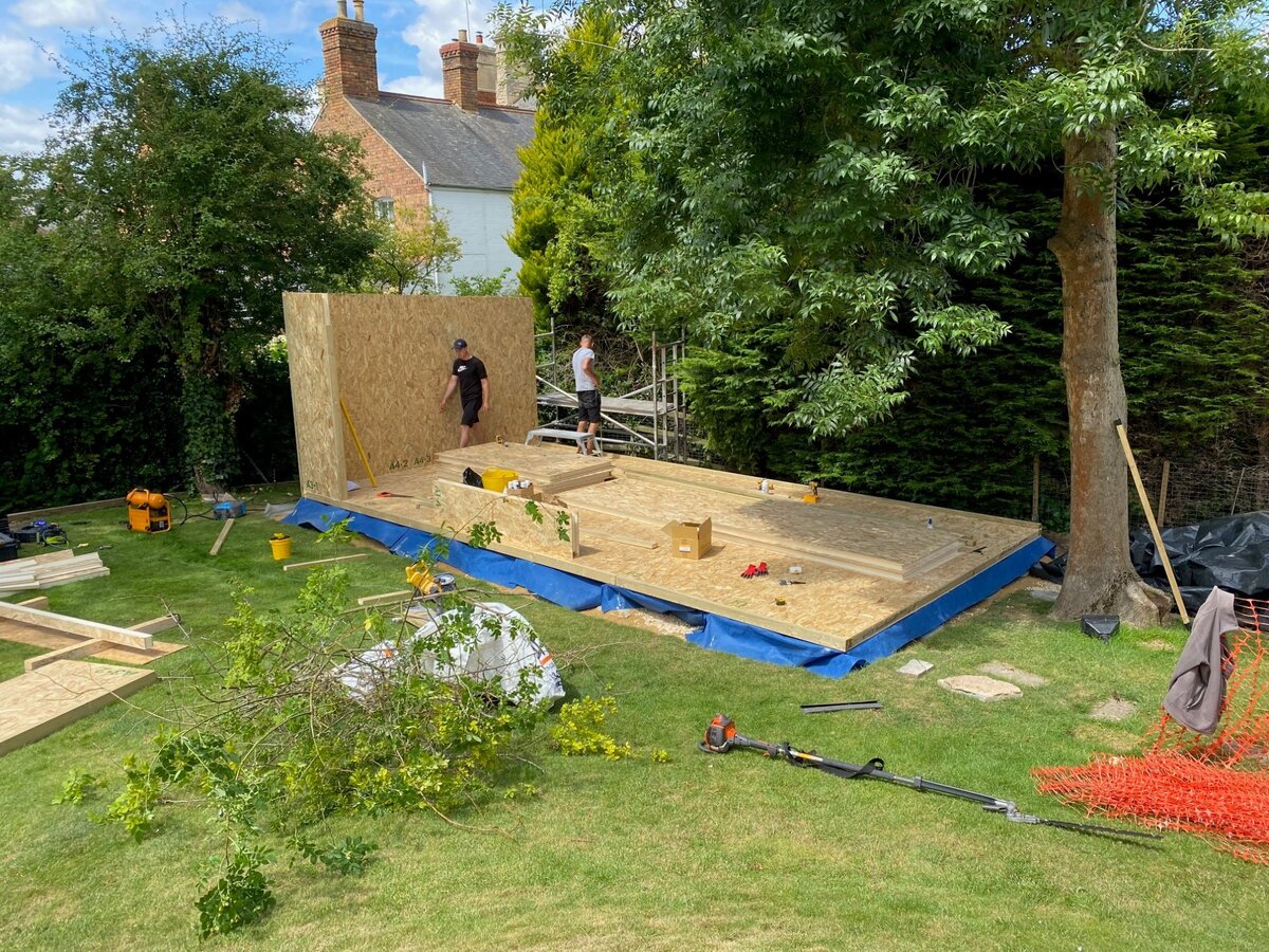 Garden room structure rising with three men working