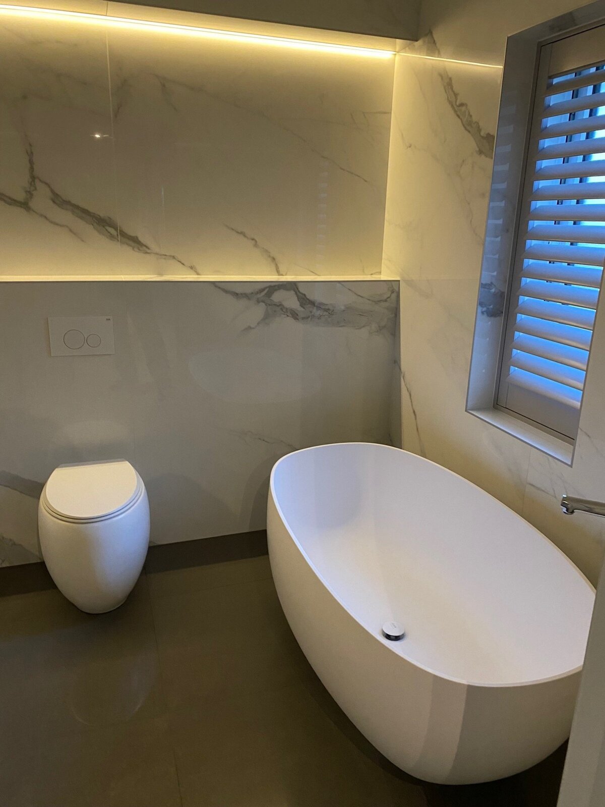 Porcelanosa bathroom with freestanding bath and LED cove